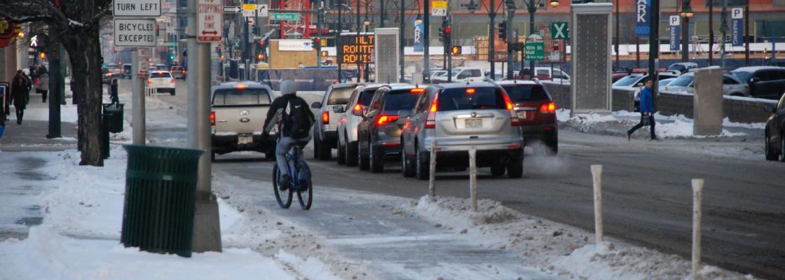A bicyclist in winter gear rides a bike in the snow in Downtown Denver.