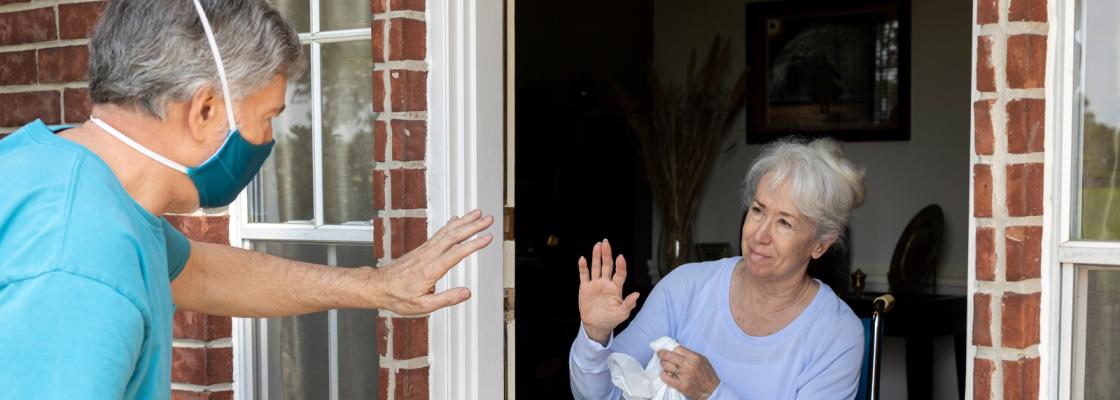 A man delivers groceries to a woman who uses a wheelchair.