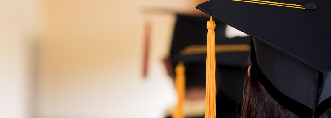 Three people wearing black robes and graduation caps are standing in a line. Only the backs of their heads are visible.