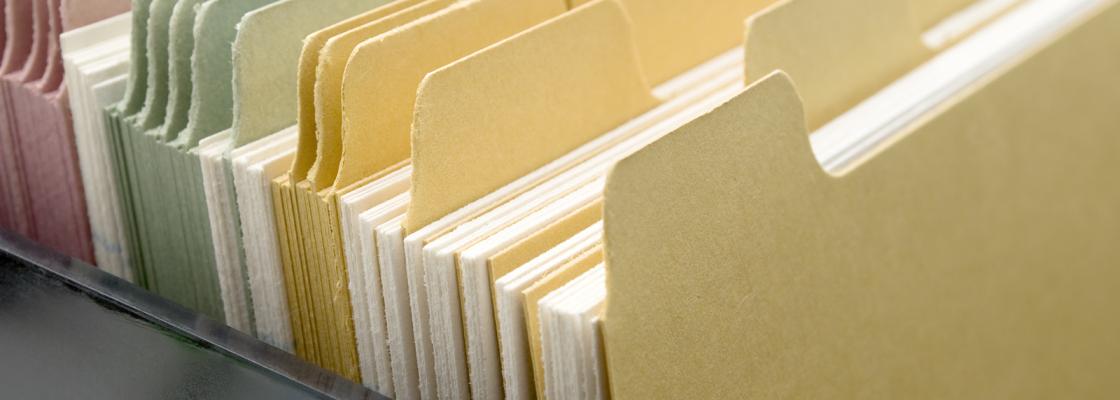 A row of colorful file folders filled with white paper.