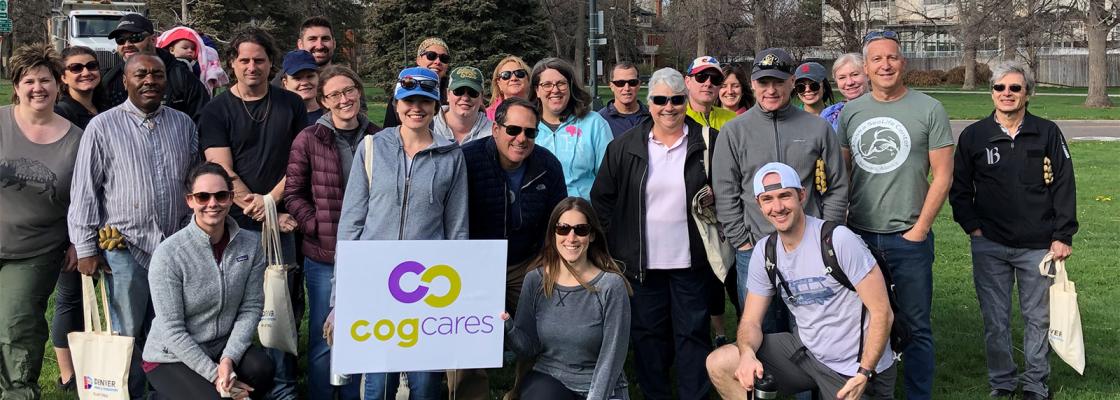 A large group of people standing in a park in front of a sign that says Cog Cares.