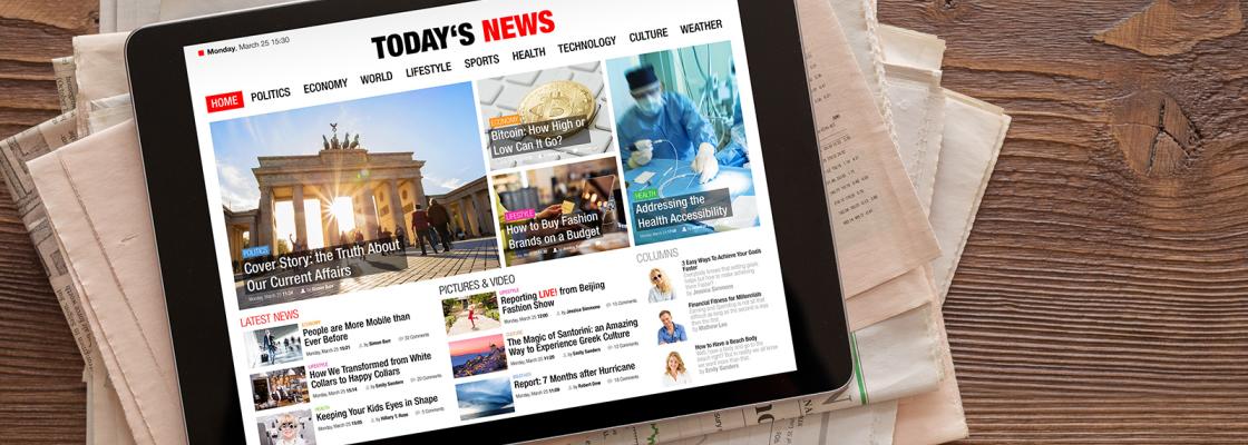 A tablet open to a webpage that says Today's News is sitting on top of a stack of newspapers.