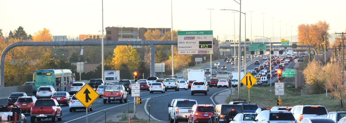 A line of cars and trucks waiting to merge onto a traffic-filled highway.