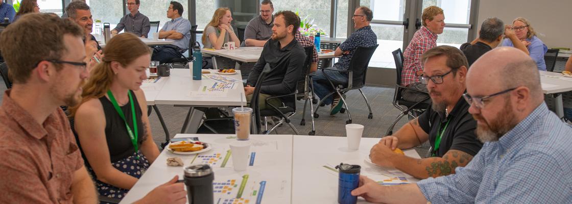 In a crowded conference room setting, four people are sitting around a table discussing issues affecting the Denver region.