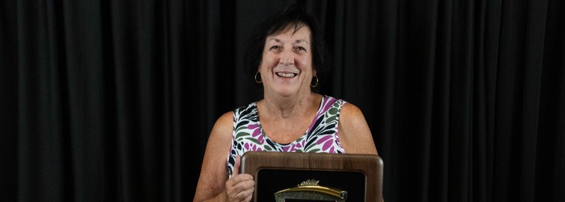 Woman holds award.