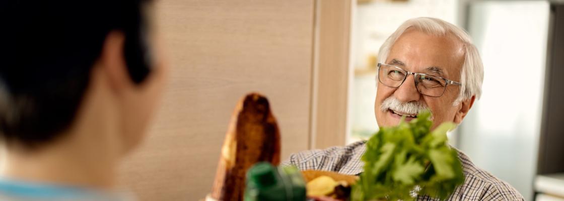 An older adult man receives groceries from a community-based organization.