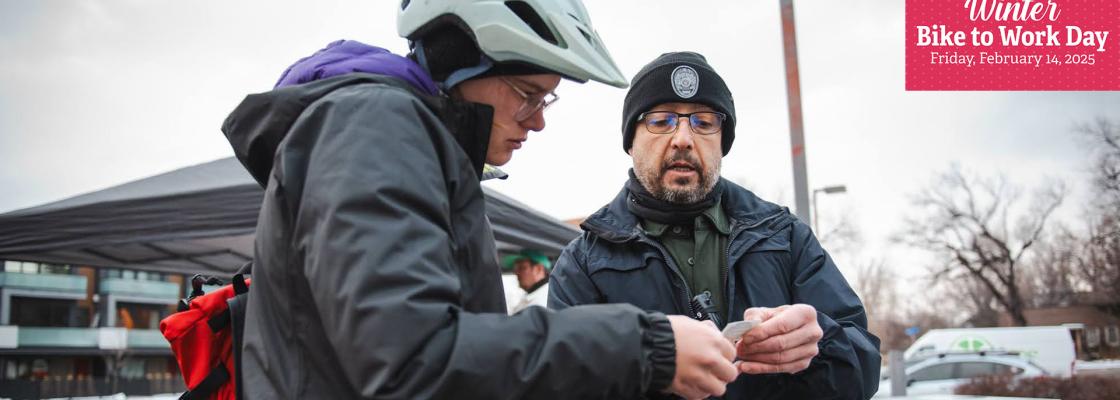 A police officer looks at a piece a paper held by a female cyclist.